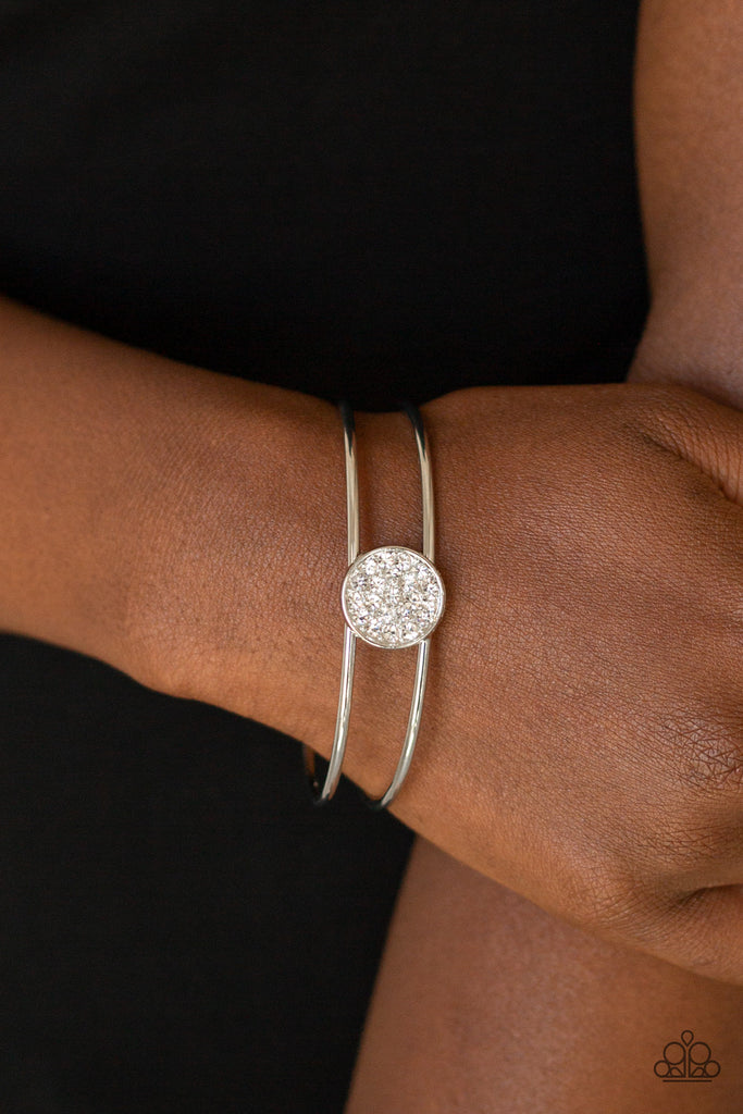 Glittery white rhinestones are encrusted along the front of a shimmery silver disc atop the center of a dainty silver cuff for a dazzling look.  Sold as one individual bracelet.