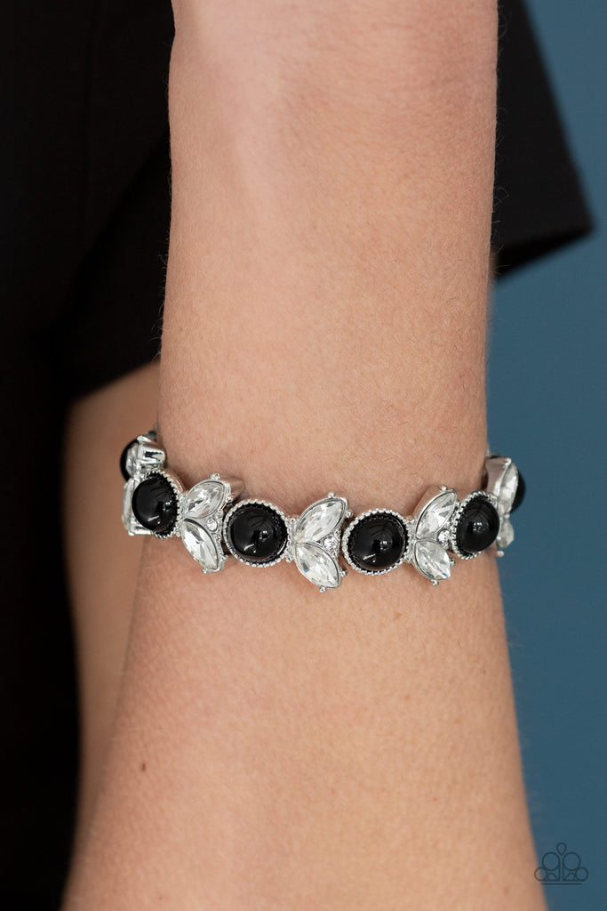 Encrusted in dazzling white rhinestones and an oversized black bead, leafy silver frames are threaded along stretchy bands around the wrist for a timeless look.  Sold as one individual bracelet.