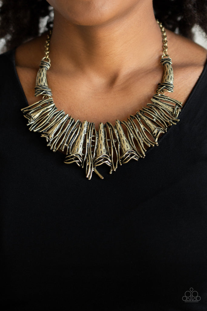 Brushed in an antiqued shimmer, a collision of glistening brass bars and hammered brass accents coalesce into an abstract statement piece below the collar for a fierce industrial look. Features an adjustable clasp closure.  Sold as one individual necklace. Includes one pair of matching earrings.