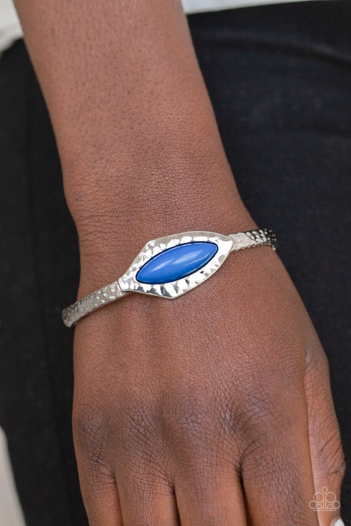 A collection of hammered silver frames are threaded along a stretchy band around the wrist. Infused with a shiny blue beaded center, an abstract frame adorns the center for a handcrafted look.  Sold as one individual bracelet.