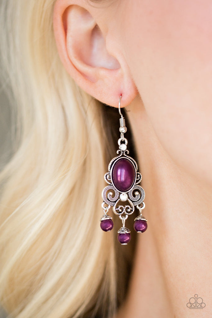 Dotted silver filigree spins around a pearly purple bead and dainty white rhinestones, coalescing into a regal frame. A pearly fringe swings from the bottom of the frame for a refined finish. Earring attaches to a standard fishhook fitting.  Sold as one pair of earrings.