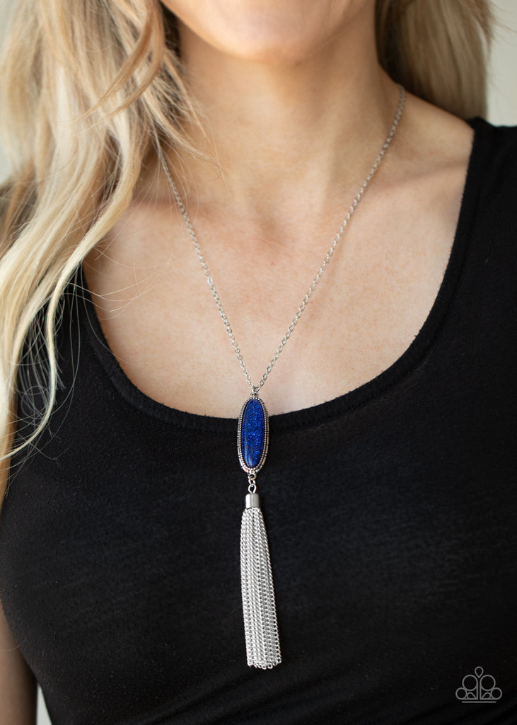 A shimmery silver tassel streams from the bottom of a glittery blue beaded pendant, creating a dazzling look at the bottom of a lengthened silver chain. Features an adjustable clasp closure.  Sold as one individual necklace. Includes one pair of matching earrings.