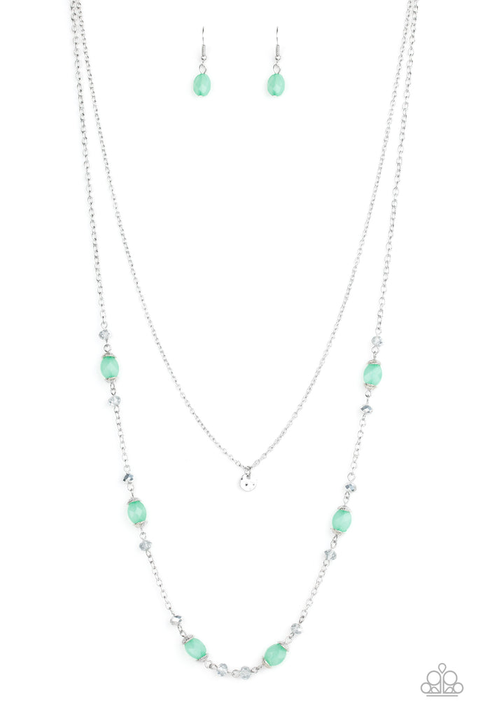 A dainty hammered disc is suspended above a glistening silver chain sparkling with dainty silver accents, metallic crystal-like beads, and opaque green beads for a whimsical look. Features an adjustable clasp closure.  Sold as one individual necklace. Includes one pair of matching earrings.
