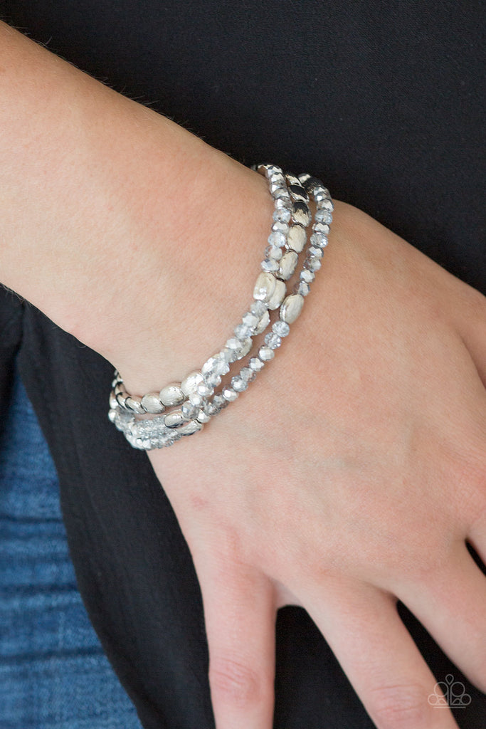 Infused with hints of silver, dainty smoky and metallic crystal-like beads are threaded along stretchy bands, creating whimsical layers across the wrist.  Sold as one set of three bracelets.