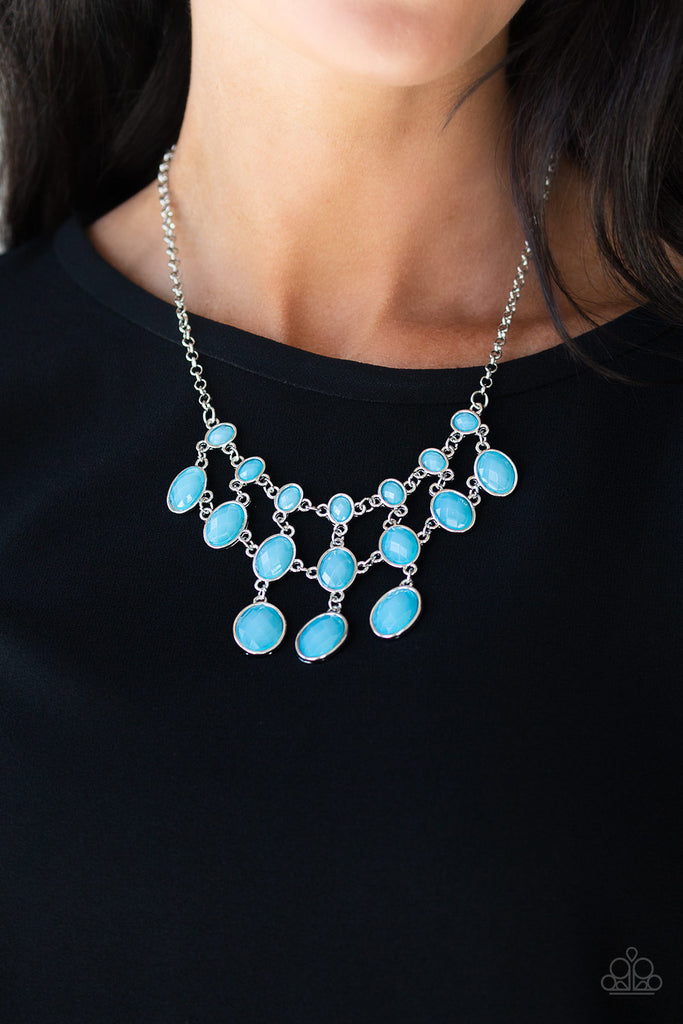 Gradually increasing in size as they cascade down the chest, rows of opalescent blue gems link together below the collar in a glamorous netted fringe. Features an adjustable clasp closure.  Sold as one individual necklace. Includes one pair of matching earrings.