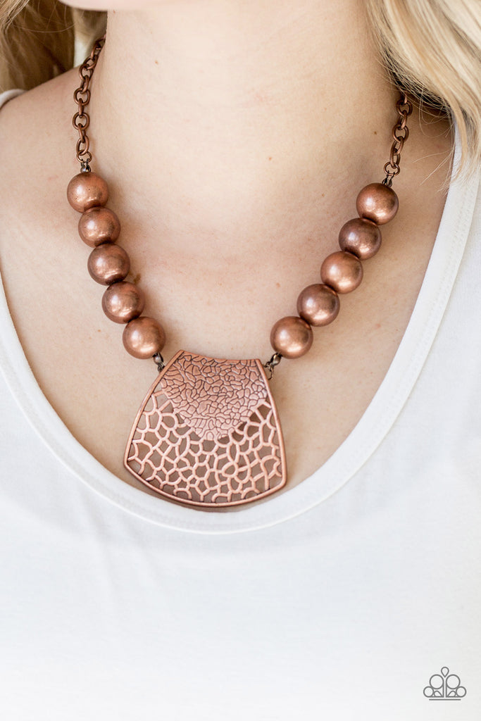 Featuring ornately stenciled and embossed details, a flared copper plate swings from a boldly copper beaded chain below the collar for a fierce look. Features an adjustable clasp closure.  Sold as one individual necklace. Includes one pair of matching earrings.