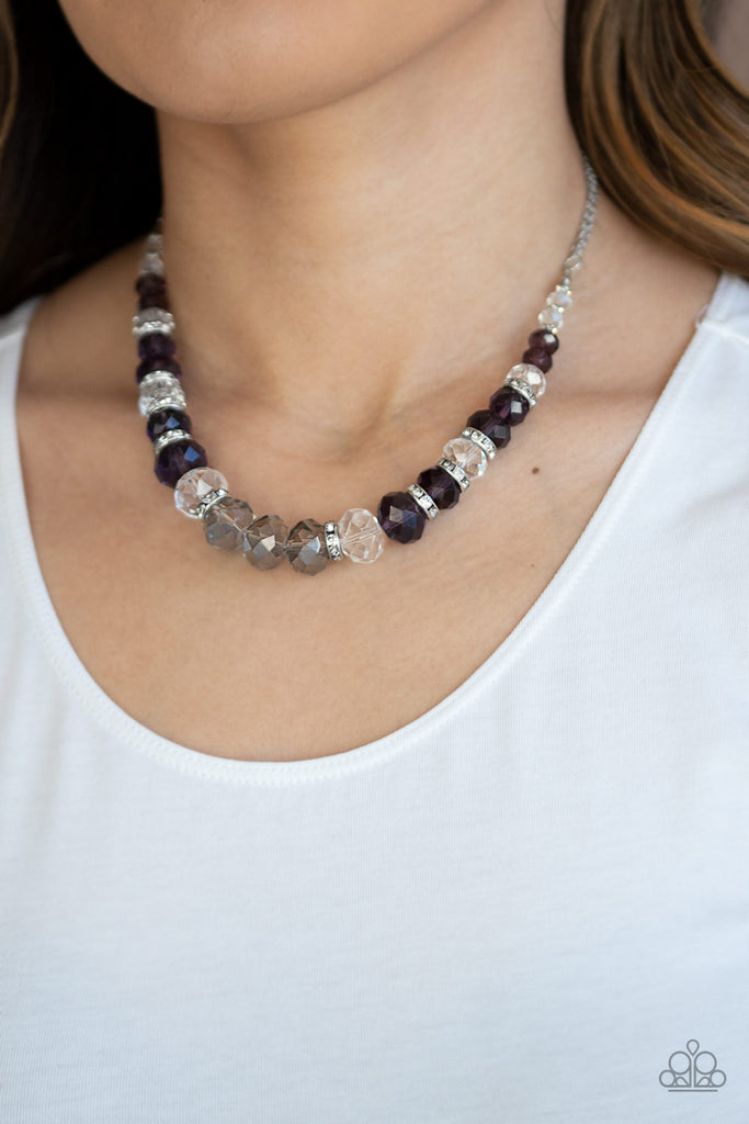 Attached to strands of shimmery silver chains, a glittery collection of purple, smoky, and white crystal-like gems and white rhinestone encrusted silver rings are threaded along an invisible wire below the collar for a glamorous finish. Features an adjustable clasp closure.  Sold as one individual necklace. Includes one pair of matching earrings.