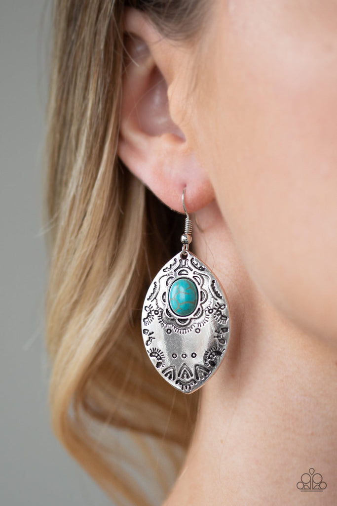 A refreshing turquoise stone is pressed into the center of a silver frame stamped with tribal inspired patterns for a seasonal look. Earring attaches to a standard fishhook fitting.  Sold as one pair of earrings.