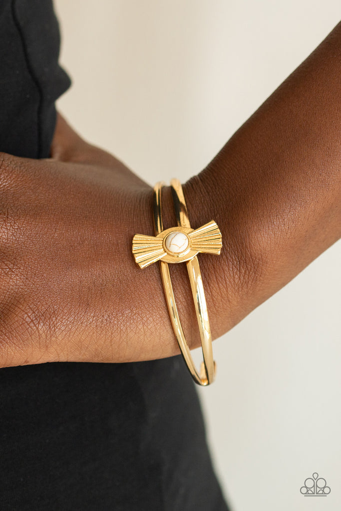 Dotted with a dainty white stone center, an antiqued gold frame flares from atop the center of a dainty gold cuff for a seasonal fashion. Sold as one bracelet