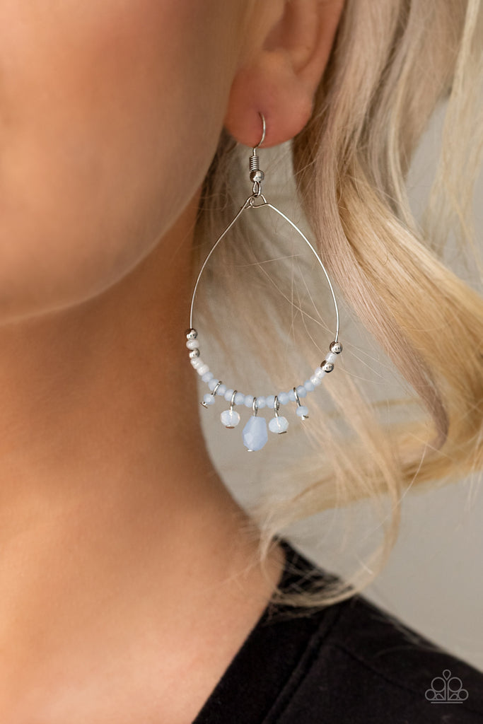 A dainty collection of silver, pearly, blue, and iridescent crystal-like beads are threaded along a dainty wire teardrop frame. Matching crystal-like beads dangle from the bottom, creating an ethereal fringe. Earring attaches to a standard fishhook fitting.  Sold as one pair of earrings.