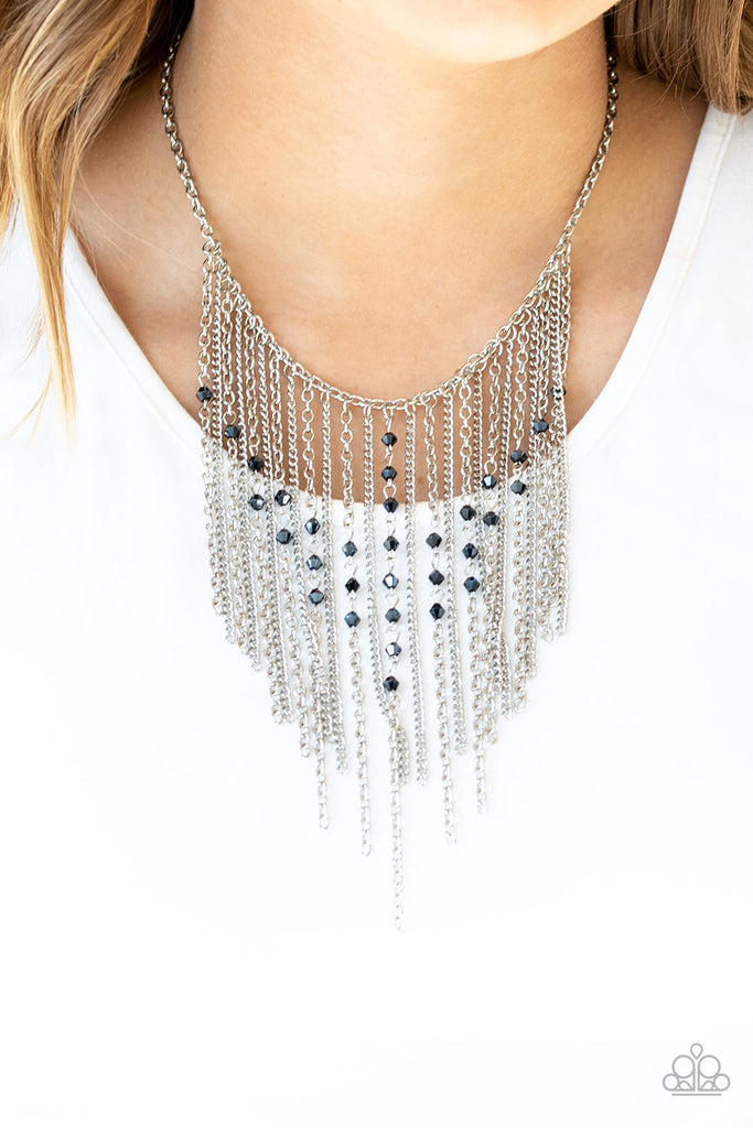 Varying in length, mismatched silver chains stream from the bottom of a classic silver chain. Faceted metallic blue crystal-like beads sporadically dot the free-falling chains, creating a statement-making fringe below the collar. Features an adjustable clasp closure.  Sold as one individual necklace. Includes one pair of matching earrings.
