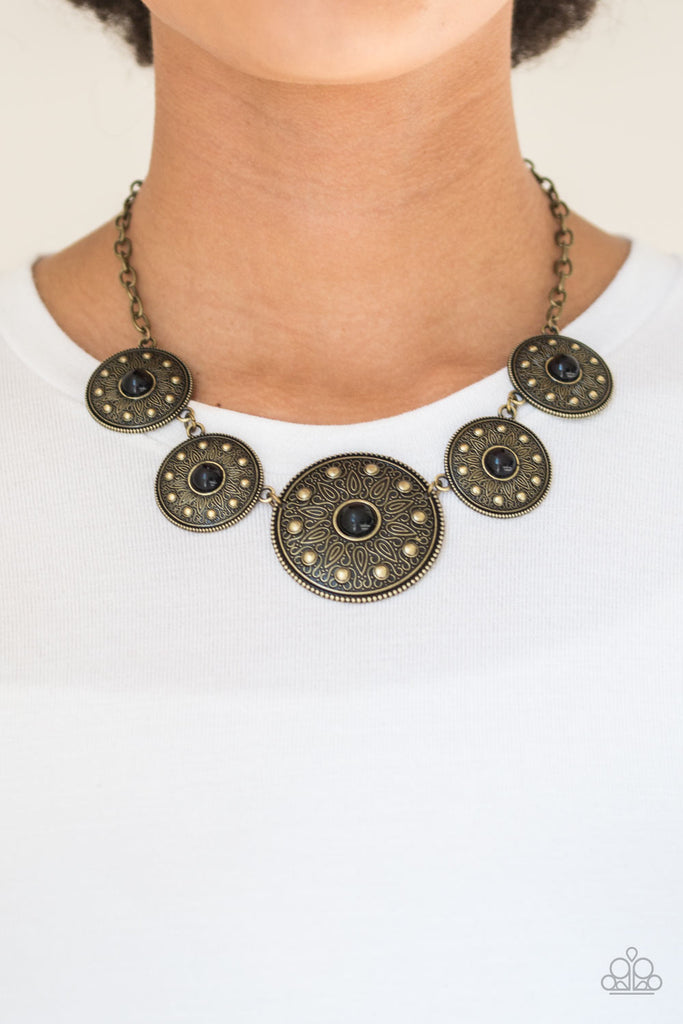 Gradually increasing in size near the center, round silver frames radiating with sunburst patterns link below the collar. Infused with shiny brass studs, the tribal inspired frames are dotted with fiery black beaded centers for a colorful finish. Features an adjustable clasp closure.  Sold as one individual necklace. Includes one pair of matching earrings.