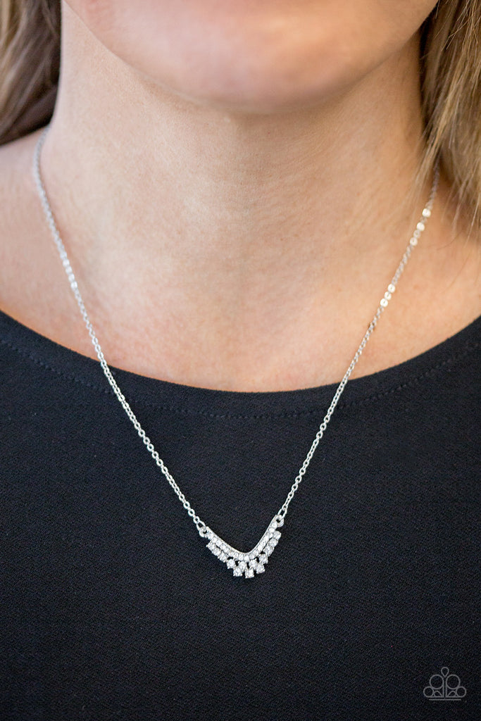 Encrusted in glassy white rhinestones, a dainty silver pendant delicately bows below the collar in a timeless fashion. Features an adjustable clasp closure.  Sold as one individual necklace. Includes one pair of matching earrings.