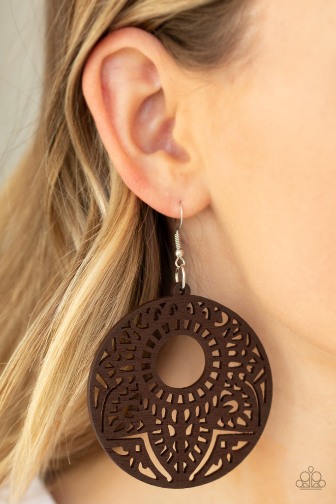 Featuring a mandala-like pattern, a brown wooden frame swings from the ear for a seasonal look. Earring attaches to a standard fishhook fitting.  Sold as one pair of earrings.