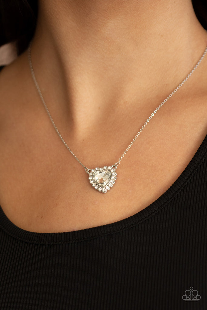 Glittery white rhinestones encircle a white heart shaped gem, creating a flirty pendant below the collar. Features an adjustable clasp closure.  Sold as one individual necklace. Includes one pair of matching earrings.