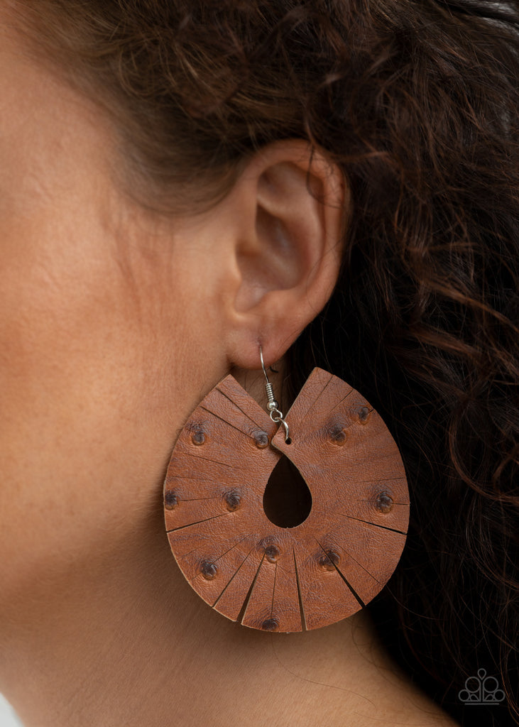 Dotted in distressed textures, a brown leather teardrop is spliced into a trendy fringe-like pattern. Earring attaches to a standard fishhook fitting.  Sold as one pair of earrings.