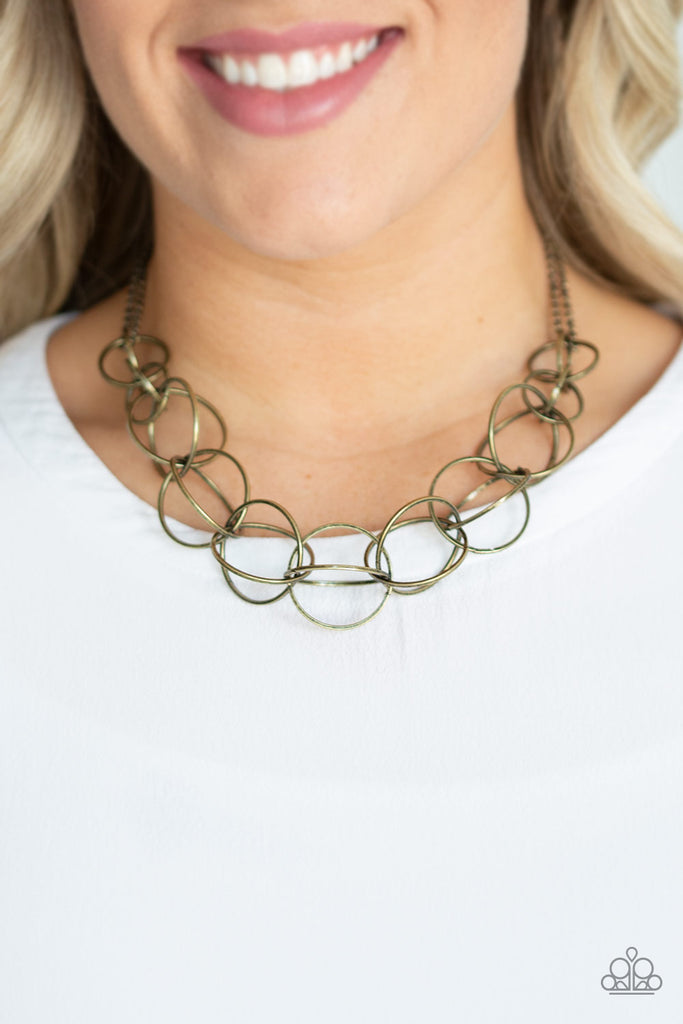 Gradually increasing in size, pairs of antiqued brass rings connect into bold stationary frames as they link below the collar for a dizzying look. Features an adjustable clasp closure.  Sold as one individual necklace. Includes one pair of matching earrings.