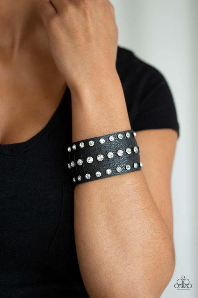 Pressed into sleek silver frames, glittery white rhinestones are studded across a thick black leather band for a sassy finish. Features an adjustable snap closure.    Sold as one individual bracelet.
