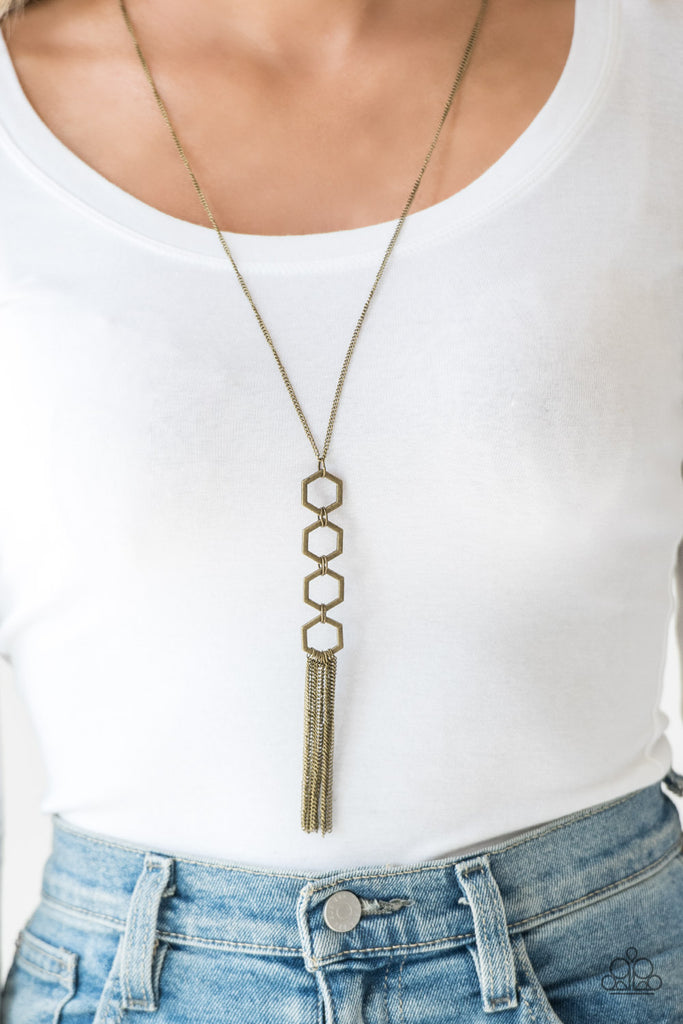 Four brass hexagon frames connect at the bottom of a lengthened brass chain, creating an edgy stacked pendant. A glistening brass tassel swings from the bottom of the geometric pendant, adding movement to the modern piece. Features an adjustable clasp closure.  Sold as one individual necklace. Includes one pair of matching earrings.