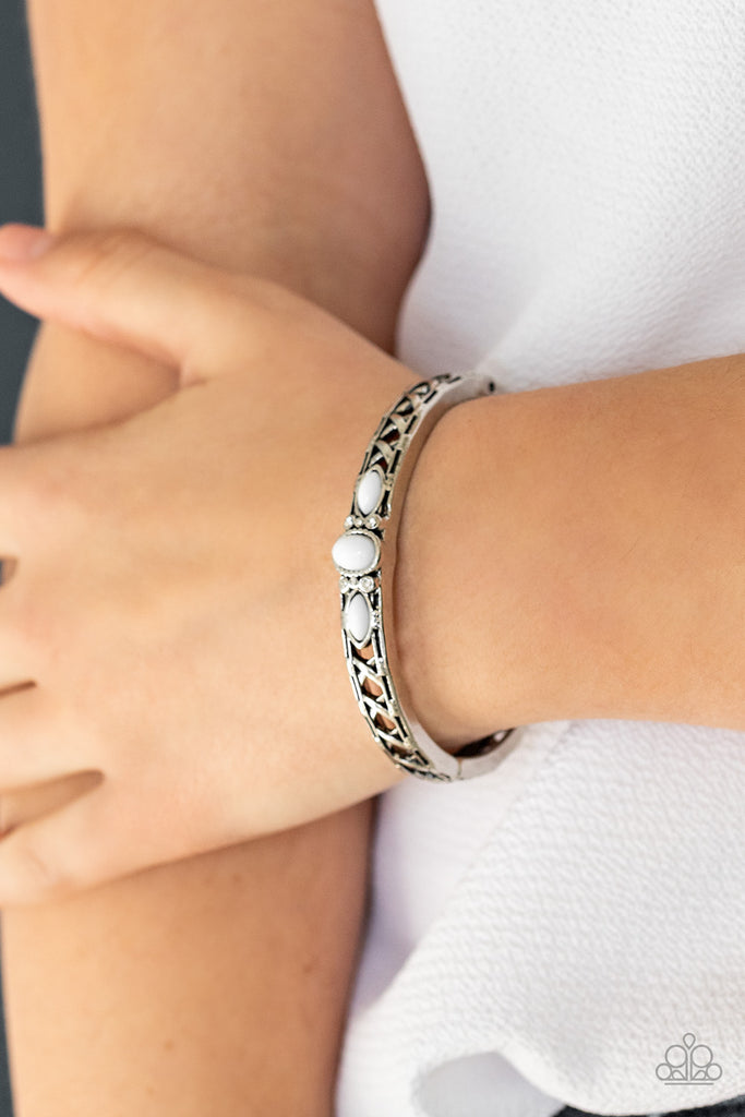 Dotted with a white beaded and glassy rhinestone encrusted centerpiece, a crisscrossing silver bangle-like cuff slides along the wrist for a whimsical look. Features a hinged closure.  Sold as one individual bracelet.