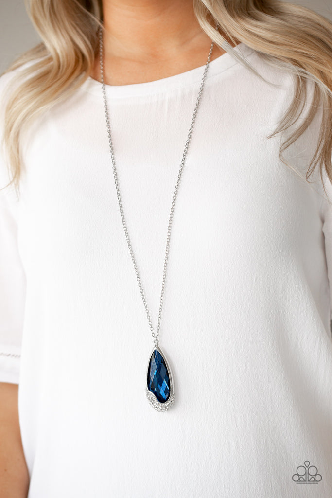 An oversized blue teardrop gem is nestled inside of an abstract silver frame that has been dipped in glassy white rhinestones. The spellbinding pendant swings from the bottom of a lengthened silver chain for a glamorous finish. Features an adjustable clasp closure.  Sold as one individual necklace. Includes one pair of matching earrings.