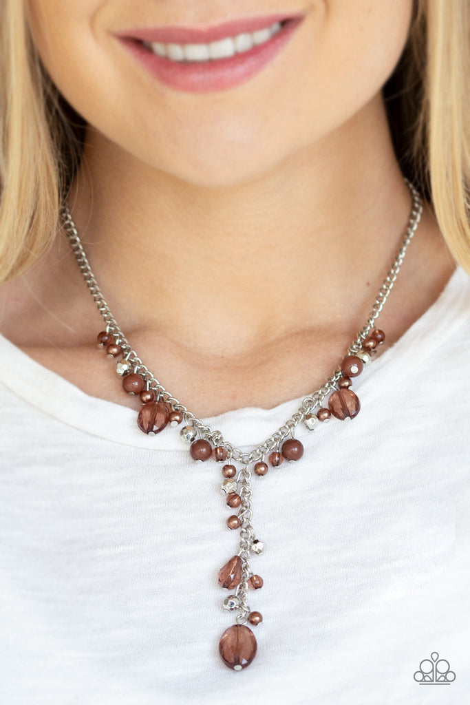 Mismatched polished brown beads, crystal-like beads, and faceted silver beads dance along a shimmery silver chain. Matching beading trickles along a single silver chain, creating a romantic extended pendant below the collar. Features an adjustable clasp closure.  Sold as one individual necklace. Includes one pair of matching earring