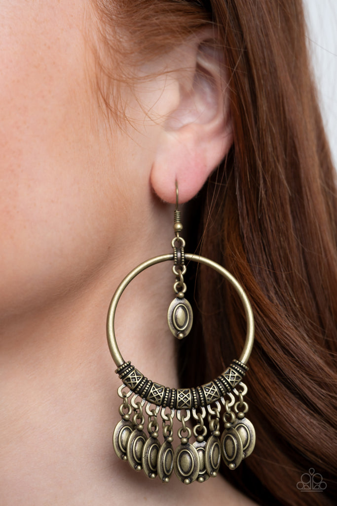 Decorative brass beads swing from the top and bottom of an ornate brass hoop, creating a tribal inspired fringe. Earring attaches to a standard fishhook fitting.  Sold as one pair of earrings.
