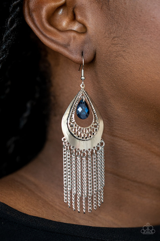 A faceted blue teardrop dangles from the top of a decorative silver teardrop frame featuring stenciled and hammered details. Dainty silver chains stream from the bottom, adding a classic fringe to the refined display. Earring attaches to a standard fishhook fitting.  Sold as one pair of earrings.
