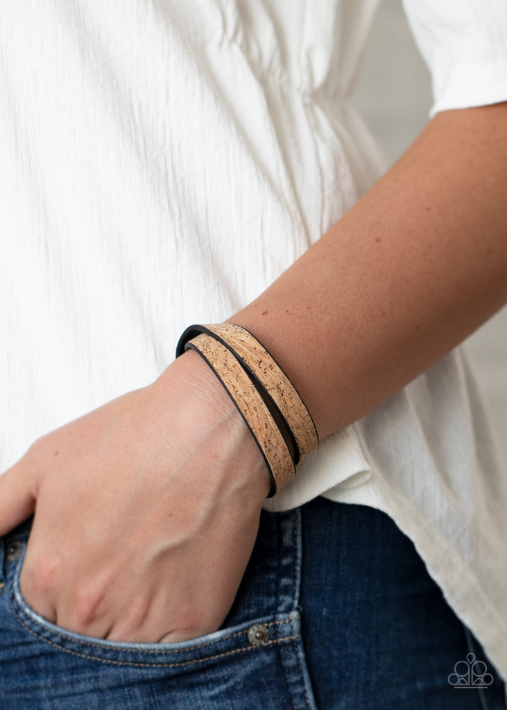 Featuring an earthy cork-like finish, a dainty black leather band delicately wraps around the wrist. The elongated band allows for a trendy double wrap design. Features an adjustable snap closure.  Sold as one individual bracelet.