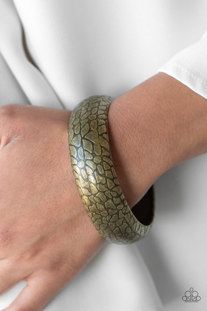 Brushed in an antiqued finish, a metallic tread-like texture is embossed across the front of a thick brass bangle for a bold look.  Sold as one individual bracelet.
