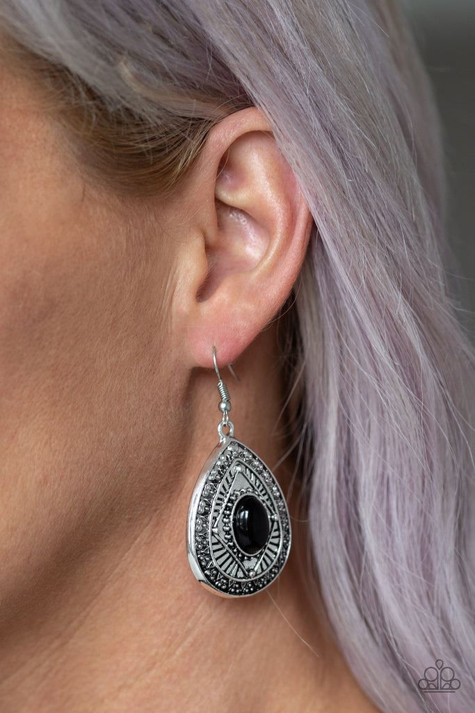 A shiny black bead is pressed into the center of a shimmery silver teardrop frame radiating with tribal inspired detail for an on-trend fashion. Earring attaches to a standard fishhook fitting.  Sold as one pair of earrings.