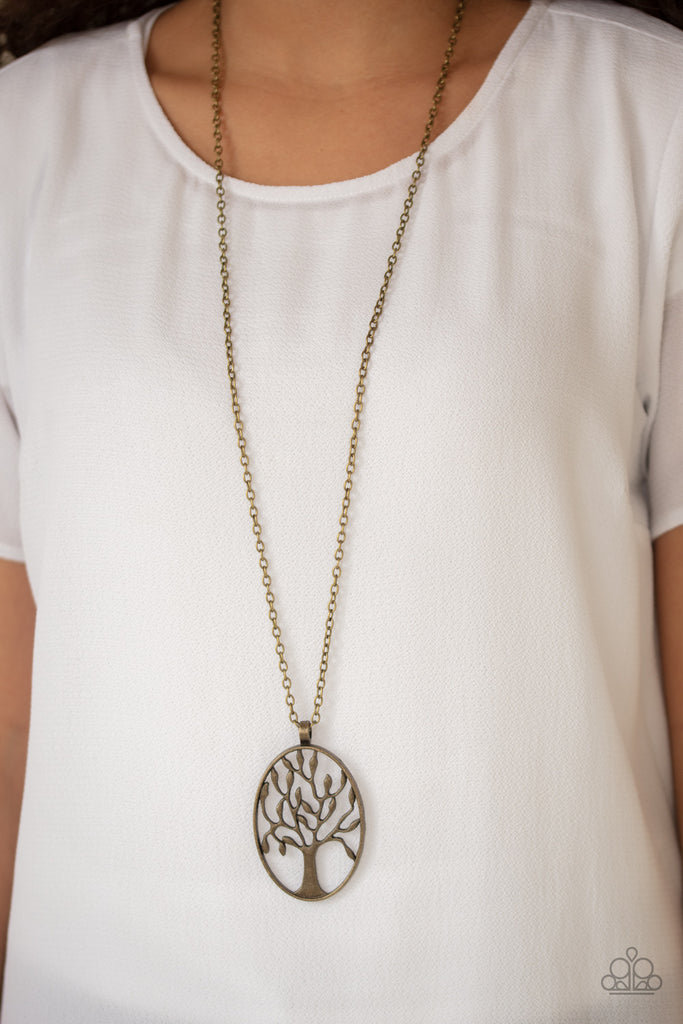An antiqued brass tree branches out across an oval frame, creating a seasonal pendant at the bottom of a lengthened brass chain for an earthy look. Features an adjustable clasp closure.  Sold as one individual necklace. Includes one pair of matching earrings.