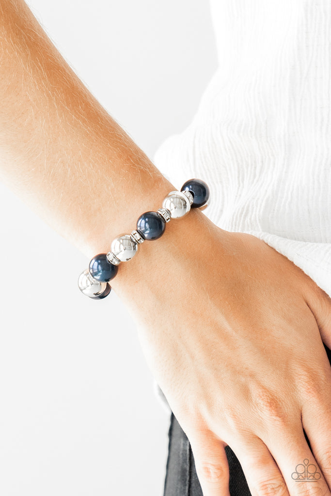 A collection of white rhinestone encrusted rings, blue pearls, and classic silver beads are threaded along a stretchy band around the wrist for a glamorous look.  Sold as one individual bracelet.