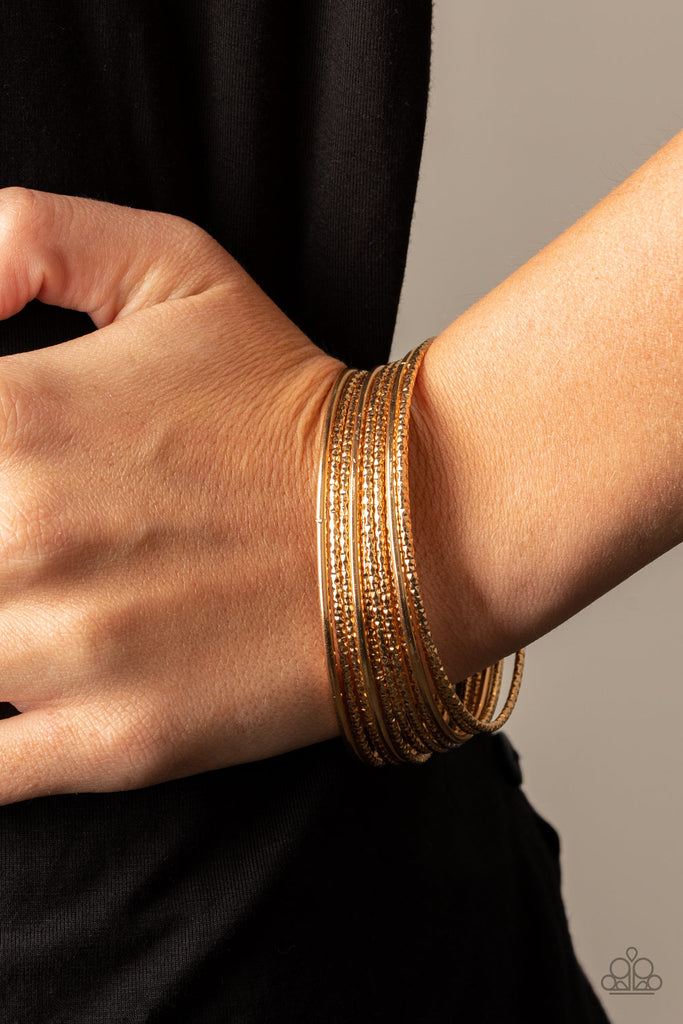 Featuring smooth and shimmery diamond-cut textures, mismatched gold bangles stack across the wrist for a casual look.  Sold as one set of eleven bracelets.