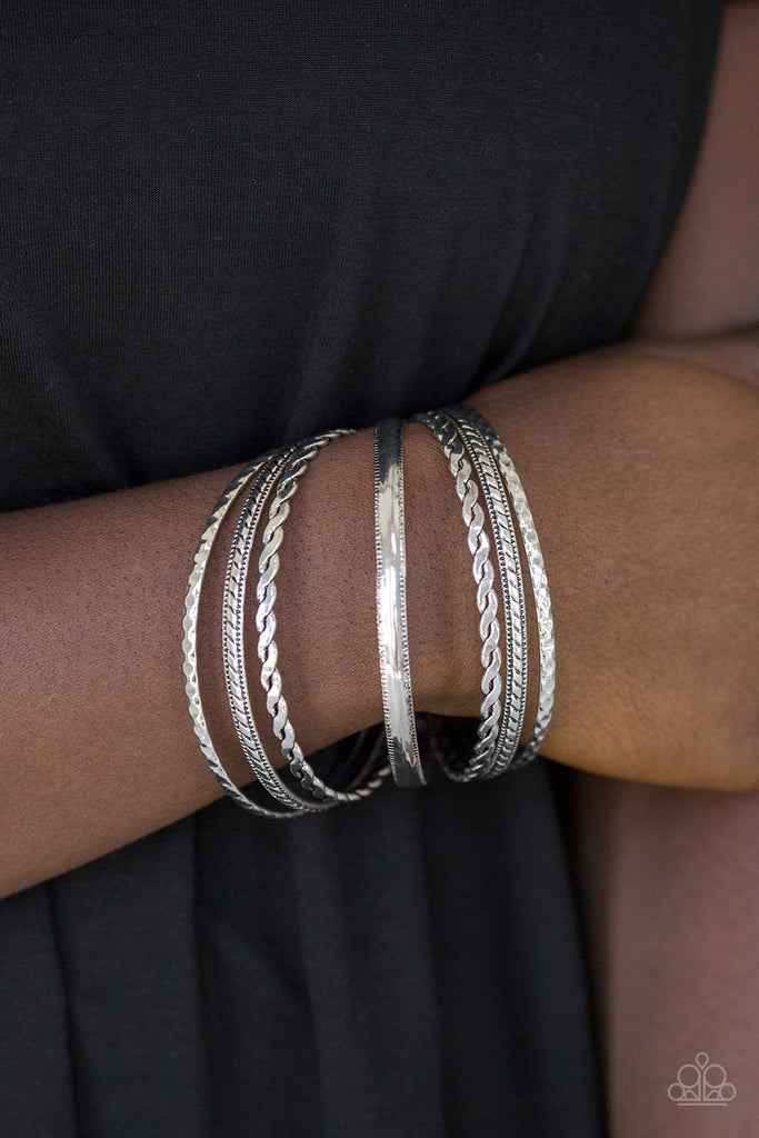 Featuring an array of tribal inspired textures, mismatched silver bangles stack across the wrist for a seasonal look.  Sold as one set of seven bracelets.  