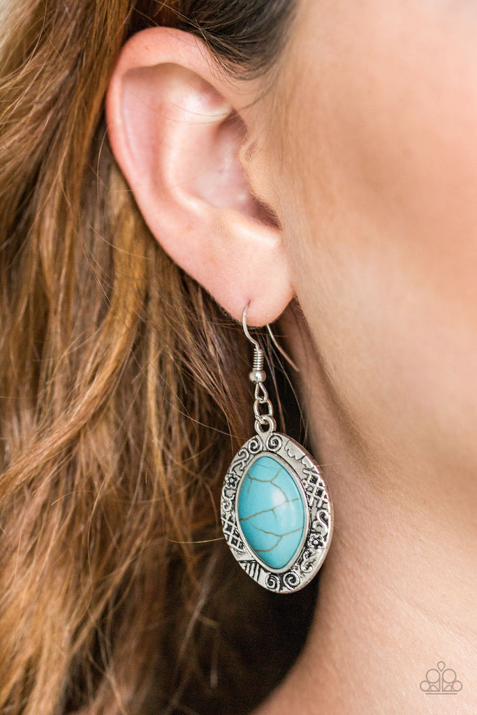 A refreshing turquoise stone is pressed into the center of a glistening silver frame radiating with floral and tribal inspired patterns for a seasonal look. Earring attaches to a standard fishhook fitting.  Sold as one pair of earrings.  