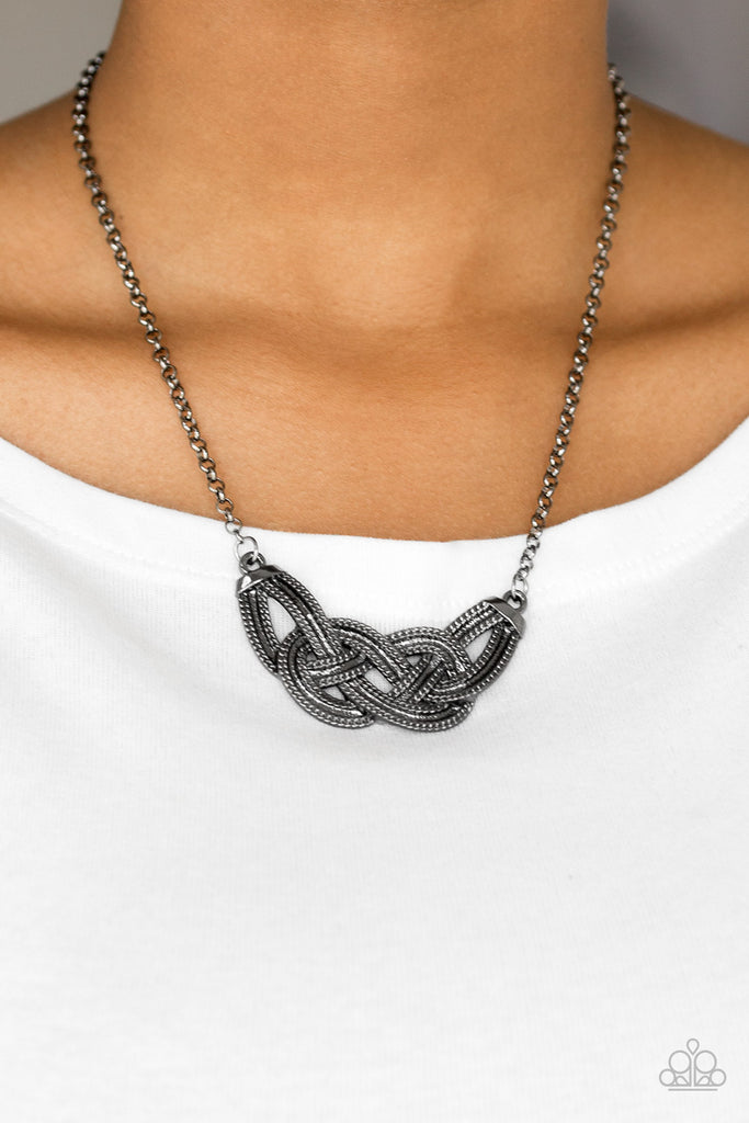 Featuring chain-like patterns, antiqued gunmetal bars knot below the collar for a bold industrial look. Features an adjustable clasp closure.  Sold as one individual necklace. Includes one pair of matching earrings.