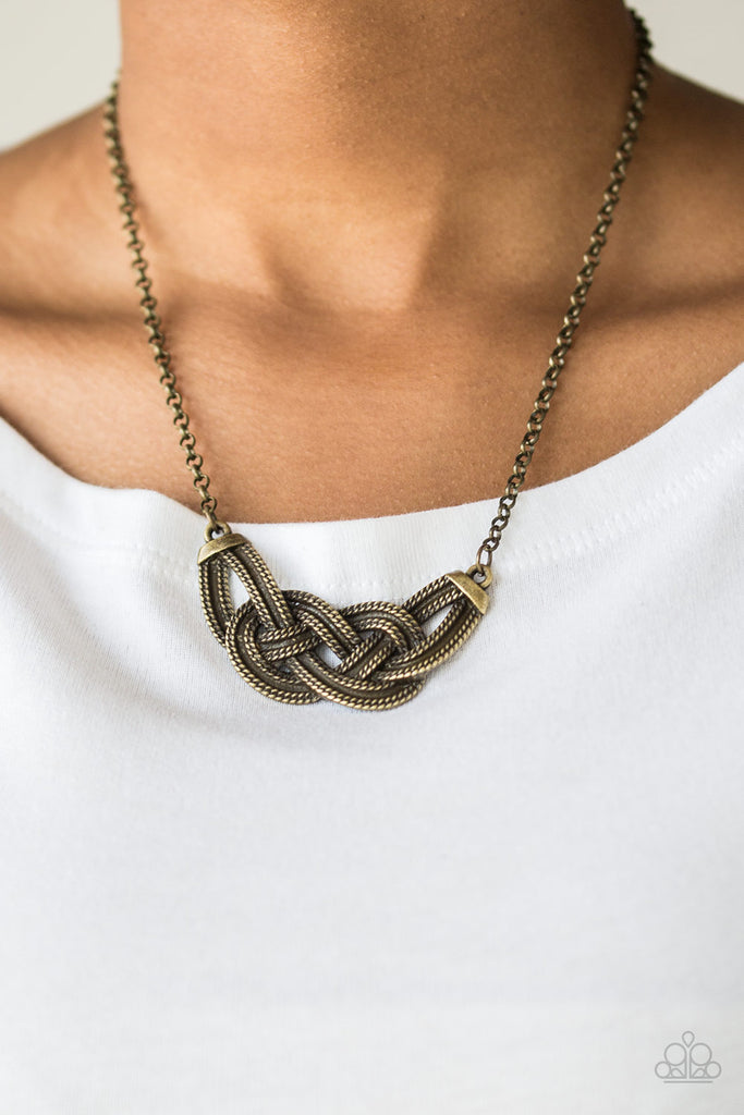 Featuring chain-like patterns, antiqued brass bars knot below the collar for a bold industrial look. Features an adjustable clasp closure.  Sold as one individual necklace. Includes one pair of matching earrings.  