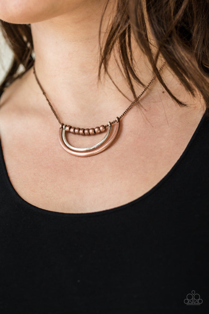 A strand of shiny copper beads give way to bowing silver and copper frames, creating an edgy pendant below the collar. Features an adjustable clasp closure.  Sold as one individual necklace. Includes one pair of matching earrings.