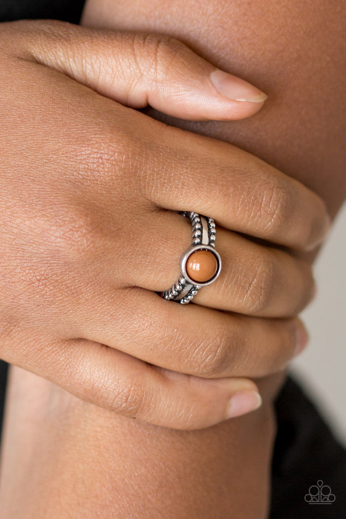 An earthy brown bead is pressed into the center of a dainty silver band radiating with studded detail for a seasonal look. Features a dainty stretchy band for a flexible fit.  Sold as one individual ring.