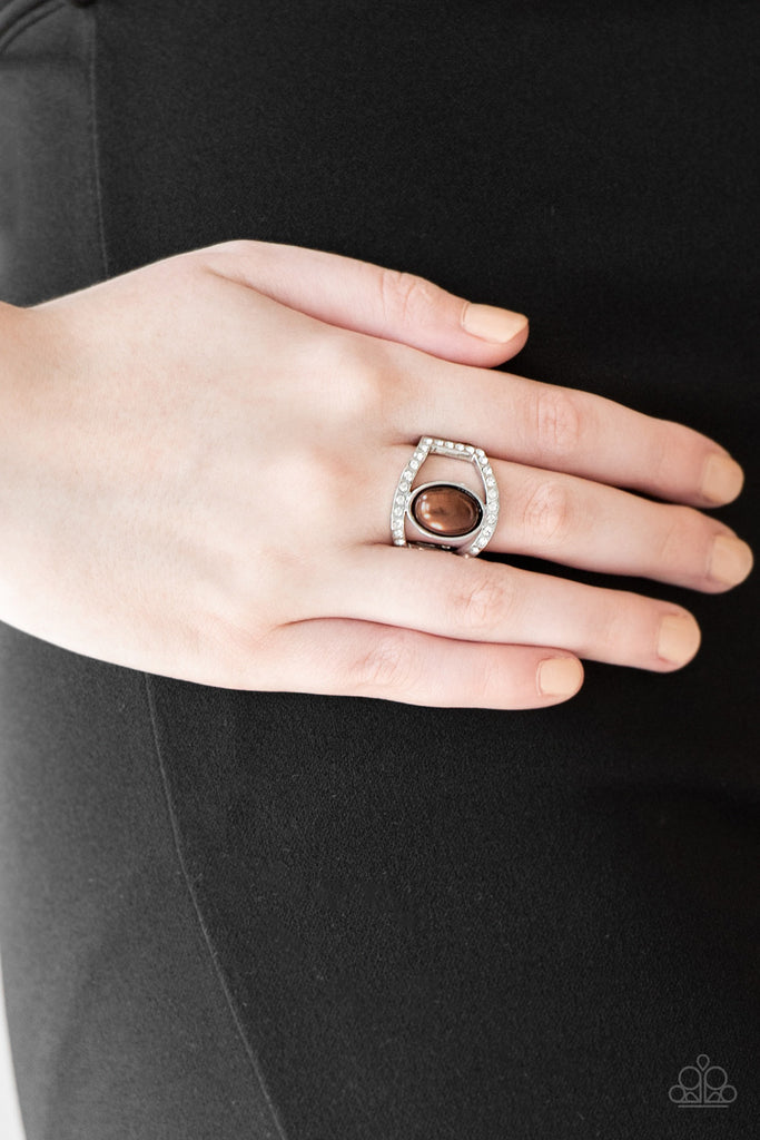 A pearly brown bead sits between two white rhinestone encrusted bands, creating the illusion of a floating centerpiece. Features a stretchy band for a flexible fit.  Sold as one individual ring.  