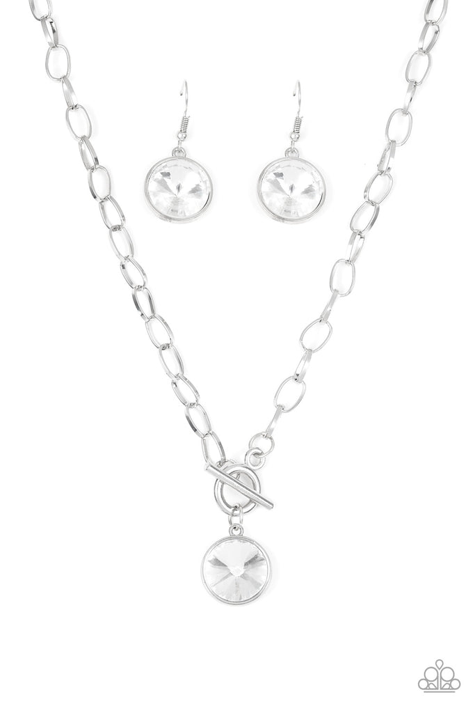 A dramatic gem white swings from the bottom of a shiny silver chain, creating a blinding pendant below the collar. Features a toggle closure.  Sold as one individual necklace. Includes one pair of matching earrings.