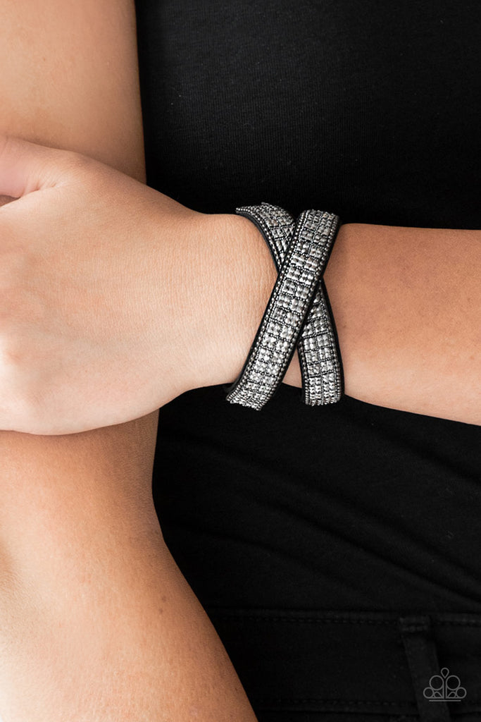 Infused with dainty gunmetal ball chain, glittery hematite rhinestones are sprinkled across a black suede band in a cube like pattern for an edgy look. The elongated band allows for a trendy double wrap design. Features an adjustable snap closure.  Sold as one individual bracelet.  