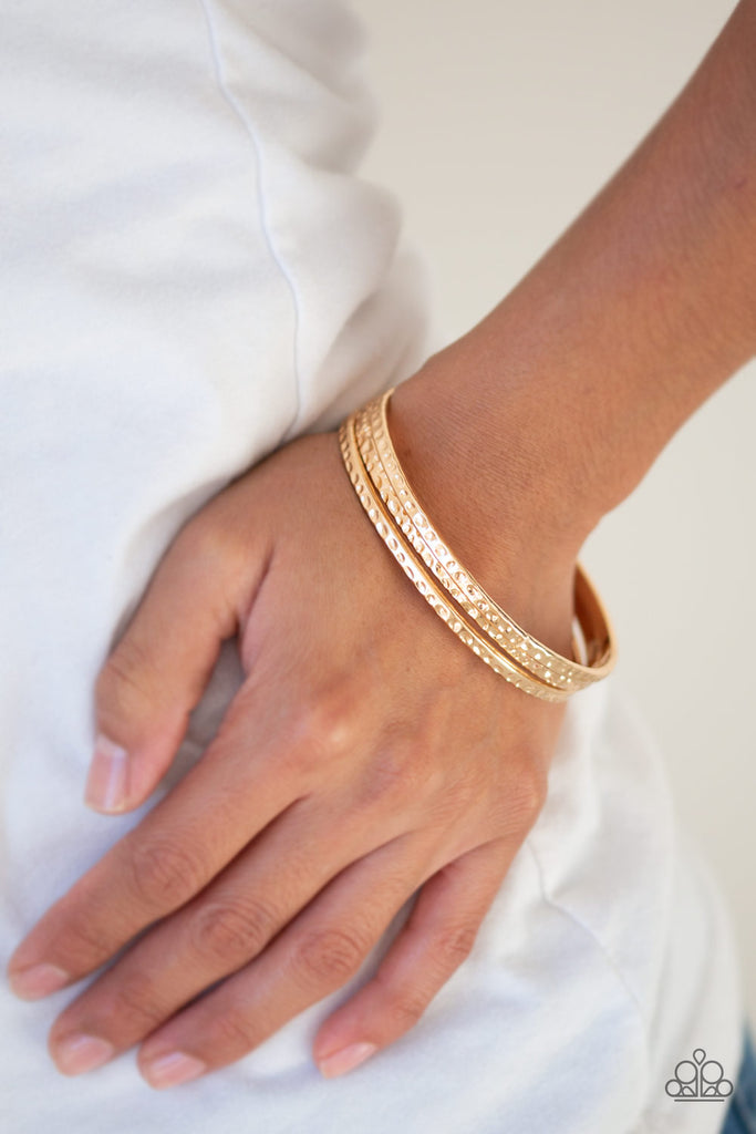 Delicately hammered in shimmery textures, a trio of glistening gold bangles glide across the wrist for a sleek look.  Sold as one set of three bracelets.