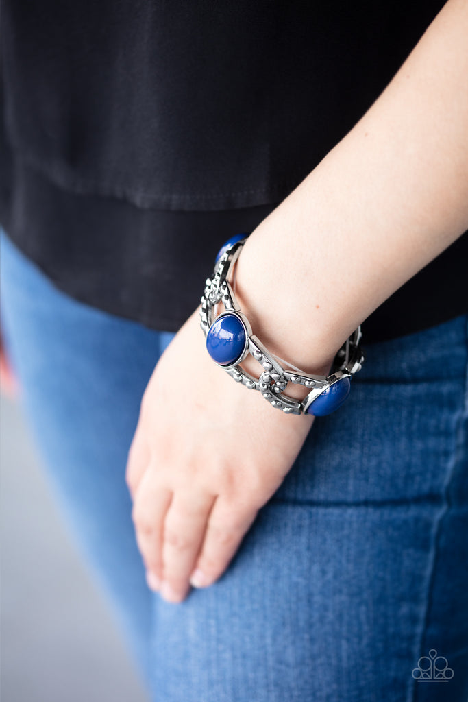Oversized Classic Blue beads and interwoven silver frames are threaded along stretchy bands around the wrist. The silver frames are dotted in antiqued studs, adding tactile texture to the colorful piece.  Sold as one individual bracelet.