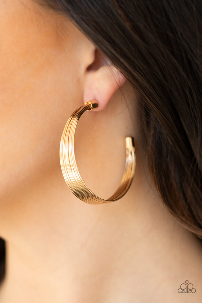 Attached to two gold fittings, wire after wire stacks into an edgy hoop. Earring attaches to a standard post fitting. Hoop measures 2" in diameter.  Sold as one pair of hoop earrings.