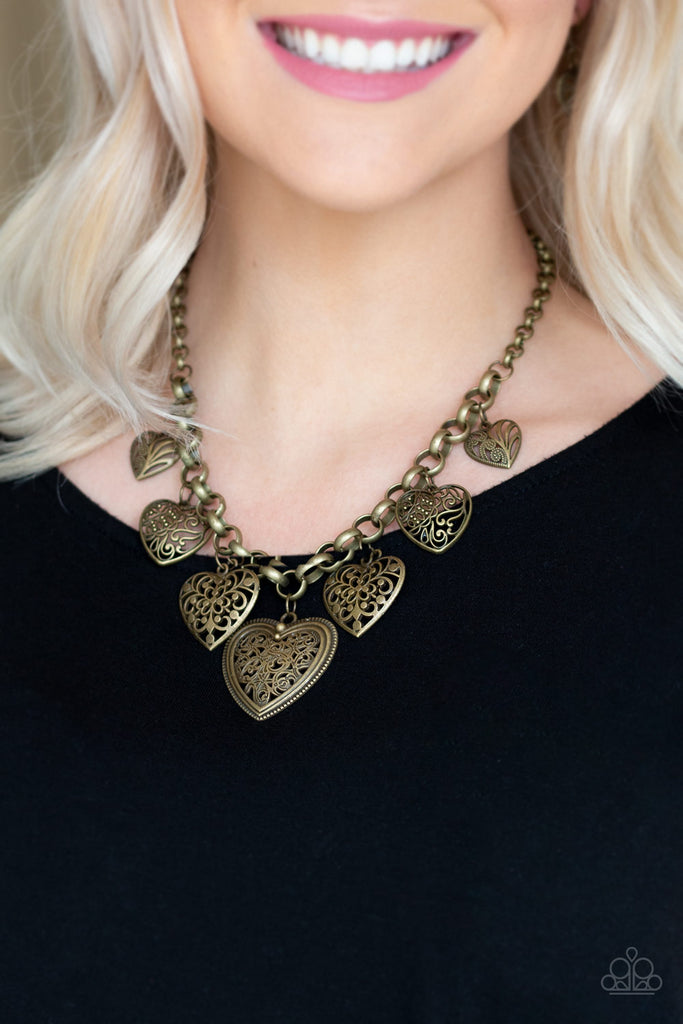 Swirling with mismatched filigree details, ornate brass heart frames swing from the bottom of a brass chain below the collar for a vintage look. Features an adjustable clasp closure. Sold as one individual necklace. Includes one pair of matching earrings.
