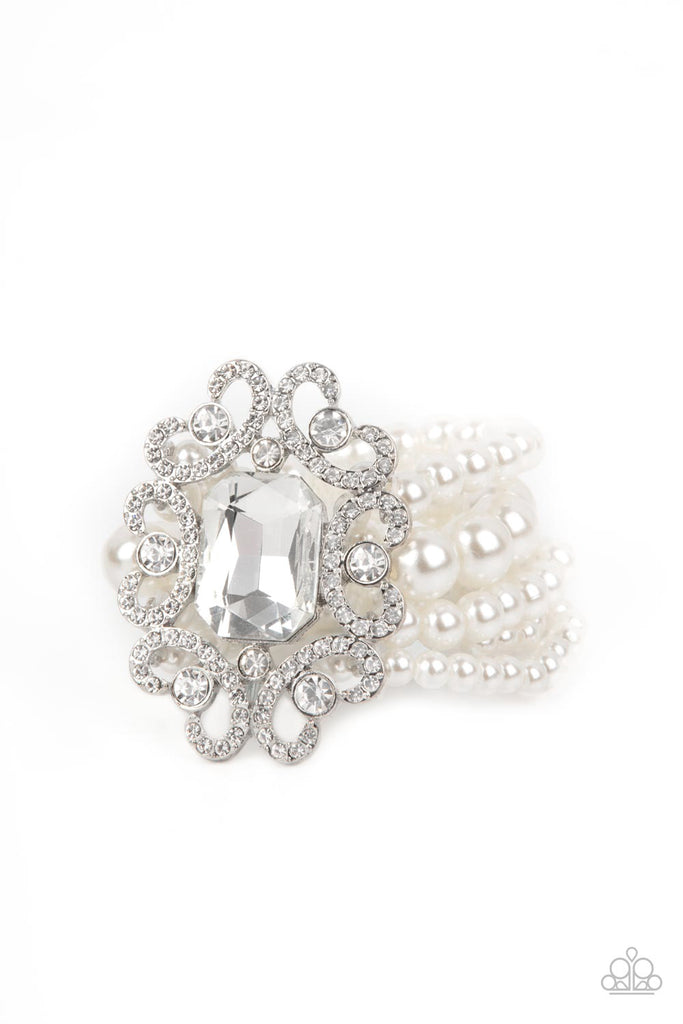 A dramatically oversized emerald cut gem adorns the center of a white rhinestone encrusted filigree filled frame. The blinding centerpiece attaches to bubbly rows of pearl beaded stretchy bracelets, creating a gorgeous statement piece.  Sold as one individual bracelet.