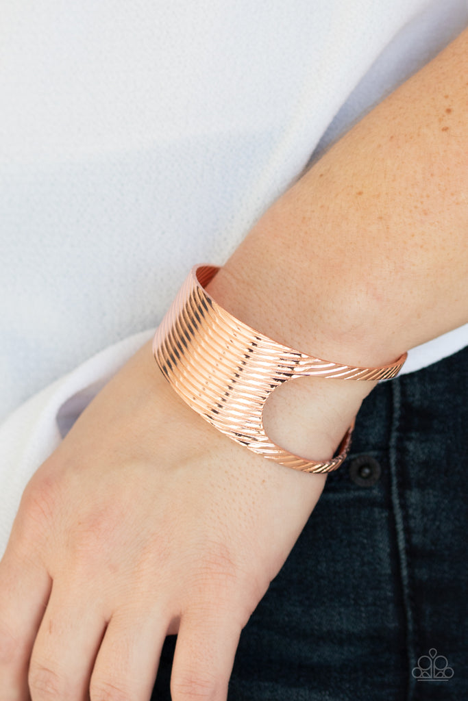 Stamped in a slanted linear pattern, a shiny copper cuff featuring an airy asymmetrical cutout wraps around the cuff for a bold industrial look.  Sold as one individual bracelet.