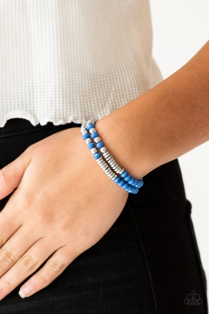 Classic silver beads, faceted Nebulas Blue beads, and dainty silver discs are threaded along stretchy bands, creating shimmery layers across the wrist.  Sold as one set of two bracelets.